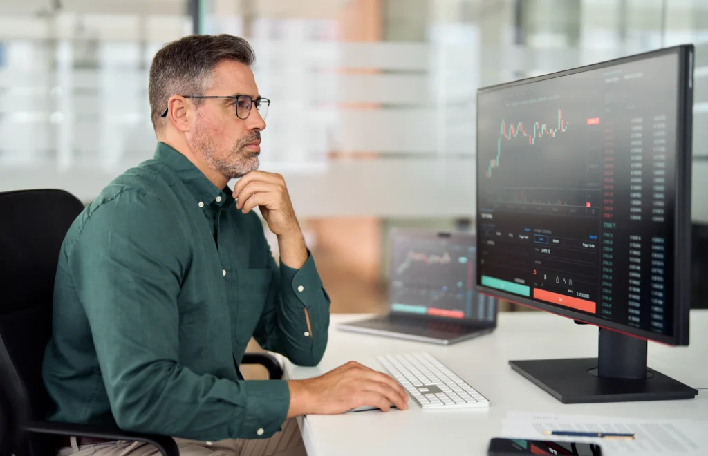 A focused trader analyzing stock charts on a computer screen while managing risk through hedging and speculation strategies.