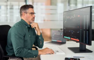 A focused trader analyzing stock charts on a computer screen while managing risk through hedging and speculation strategies.