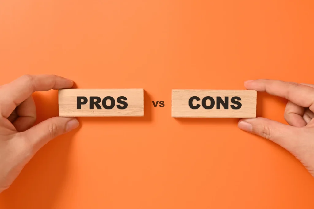 Hands holding wooden blocks labeled “Pros” and “Cons” on orange background — concept of Commodity Trading pros and cons 2025.