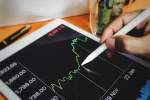 A trader analyzing a stock price chart on a tablet, using a stylus to study market fluctuations — representing the concept of Gamma in Investing and market sensitivity.