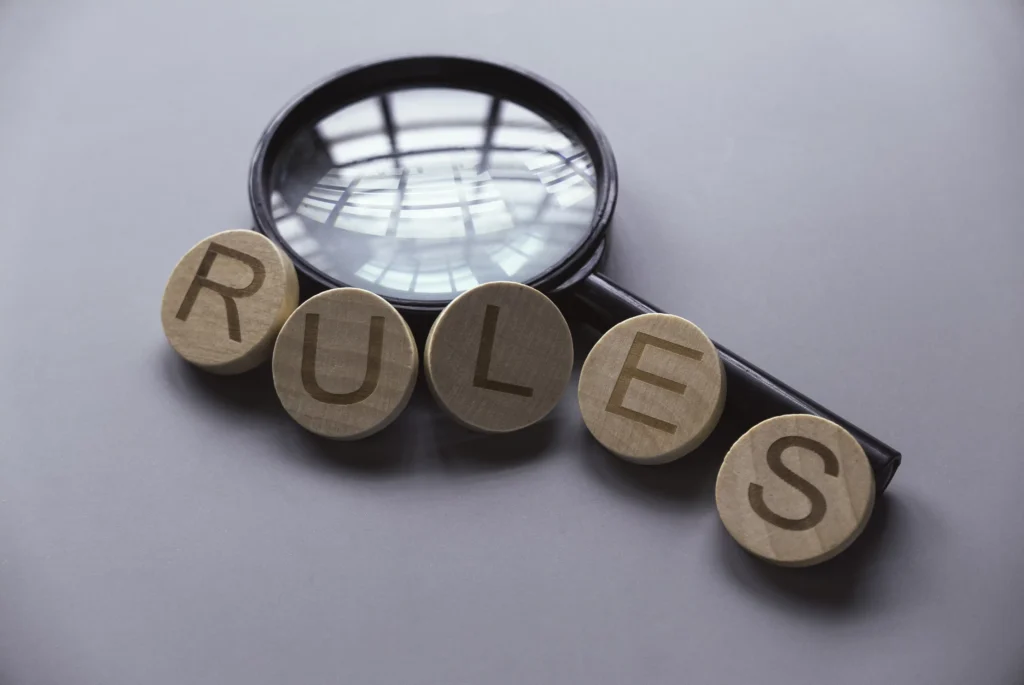 Magnifying glass over wooden blocks spelling “RULES,” symbolizing the essential rules for picking stocks in intraday trading.