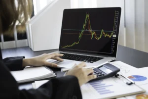 A trader analyzing a live market chart on a laptop, reviewing copy trading performance data and profitability trends in 2025.