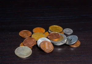 Mixed collection of different metal coins placed on a dark wooden table.