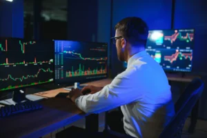Trader analyzing multiple chart timeframes on dual monitors in a forex trading setup.