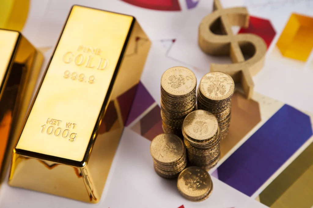 Gold bars and stacked gold coins placed on financial charts representing Gold ETF investment.
