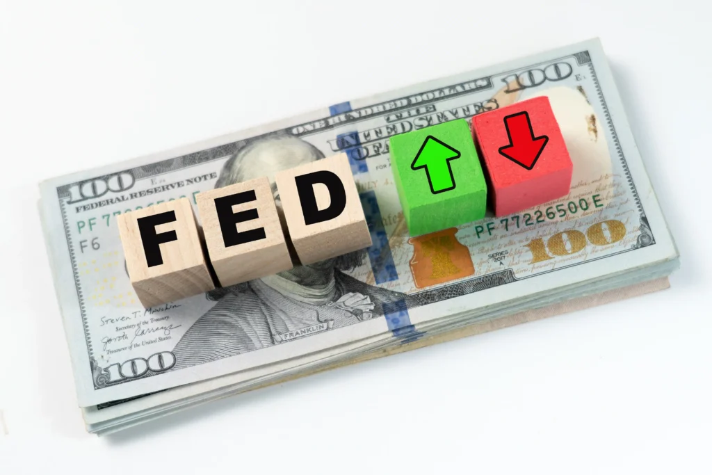 Image showing the economic impact of expected Fed rate cuts in December with dollar bills and rate direction symbols.