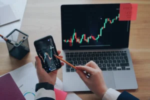 Trader analyzing bullish candlestick patterns on phone and laptop screen for daily chart analysis in 2025.