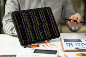 Trader analyzing RSI + MACD Multi Timeframe Strategy charts on tablet with forex and performance data on desk.