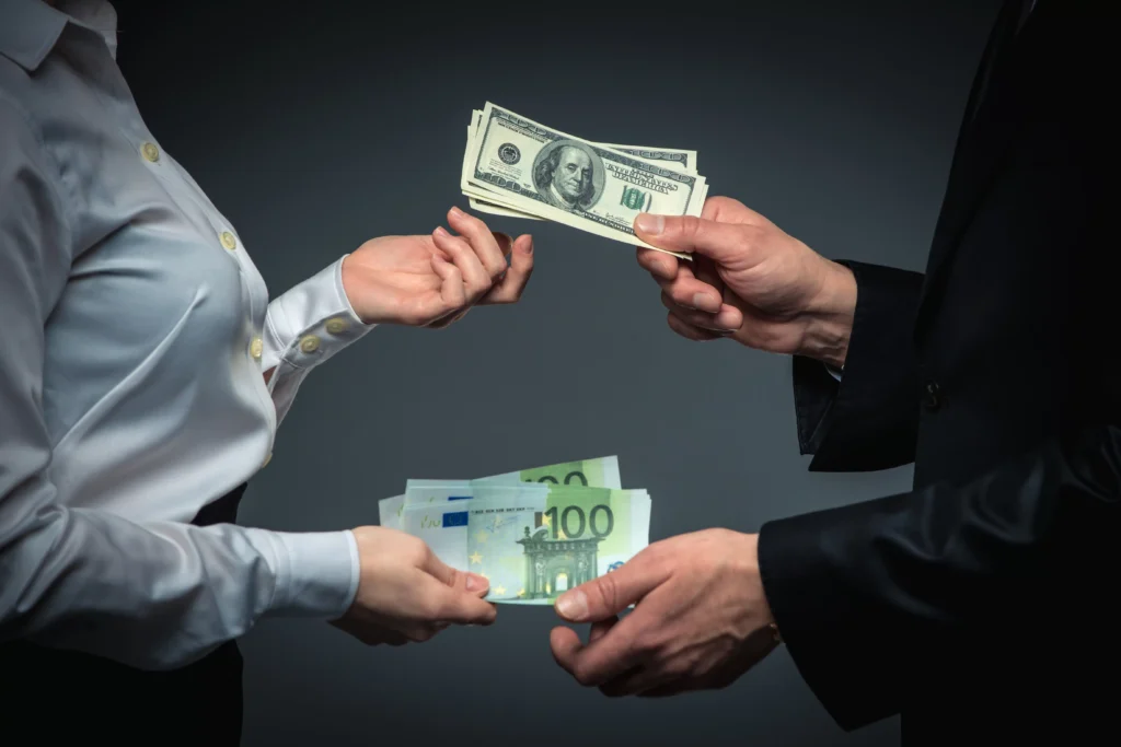 Business professionals exchanging US dollars and euros, illustrating Foreign Exchange Risk and currency value fluctuations.