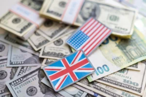 British Pound and US Dollar flags placed over stacks of currency notes representing GBP/USD trading movement.