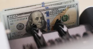 Stack of U.S. hundred-dollar bills being counted, symbolizing U.S. Dollar Strength in 2025–2026 global markets