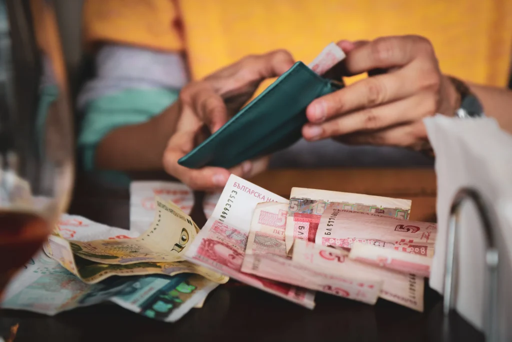 Person handling multiple foreign currency notes at a table, symbolizing USD vs INR money decisions