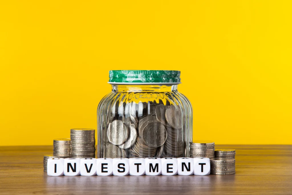 A glass jar filled with coins representing savings and smart financial planning for the Best Investment Plans 2026.